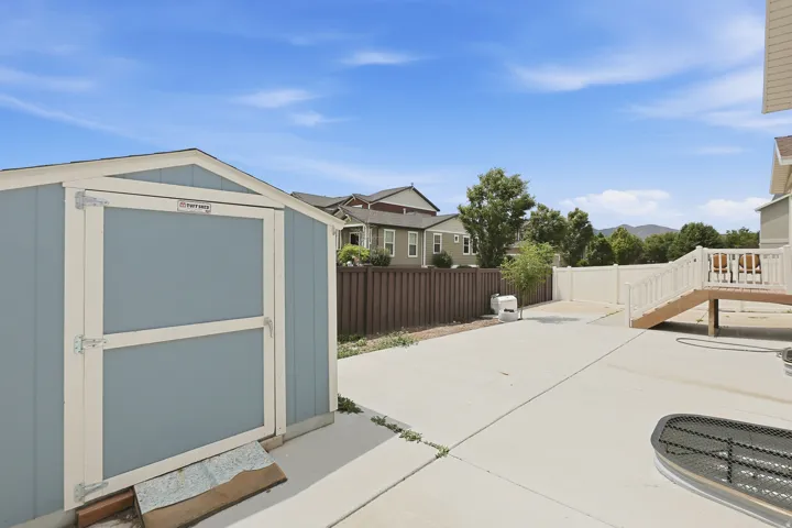 Spacious backyard featuring an expansive concrete patio, a storage shed, and low-maintenance landscaping. The fenced yard offers plenty of room for outdoor activities and additional storage.