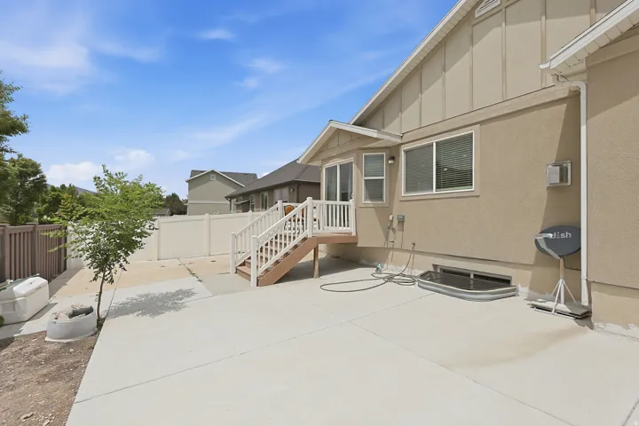 Low-maintenance backyard featuring a spacious concrete patio, elevated deck with stair access, and fenced yard—ideal for outdoor dining, relaxing, or entertaining.