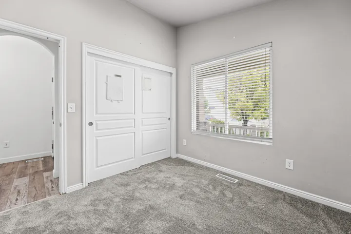 Another view of the secondary bedroom highlighting the spacious closet, neutral color palette, and bright window overlooking the front yard.