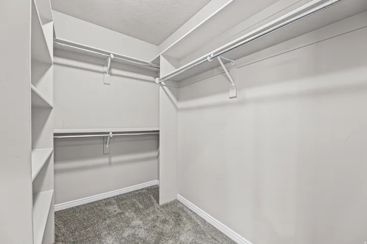Spacious walk-in closet with built-in shelving and multiple hanging areas designed to maximize organization and storage.