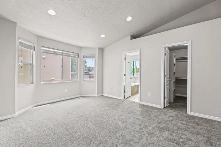 Generous primary bedroom featuring large windows that bring in natural light and an adjoining en-suite bathroom and walk-in closet.