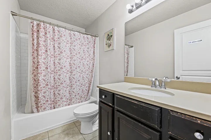 Full bathroom featuring a vanity with storage and a tub/shower combination in a clean, functional design.