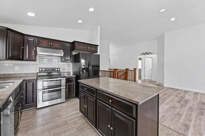 Open kitchen featuring a large center island, abundant dark cabinetry, stainless steel appliances, and generous workspace. The open layout connects seamlessly to the adjacent living and dining areas.