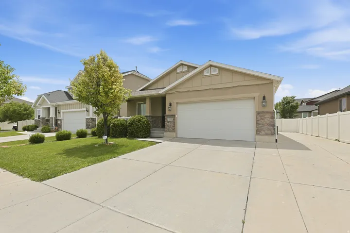 49 foot RV parking on side of garage with another view of the home's attractive front exterior showcasing the wide driveway, manicured lawn, mature landscaping, and attached two-car garage.