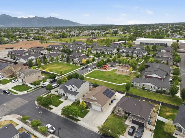Elevated aerial perspective showcasing the surrounding residential neighborhood, nearby open spaces, and scenic mountain backdrop.