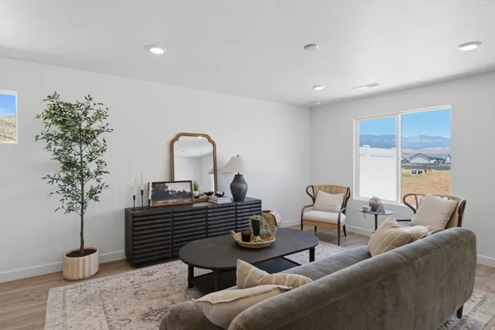Open-concept living area featuring light wood-finish flooring, recessed ceiling lighting, and a large window