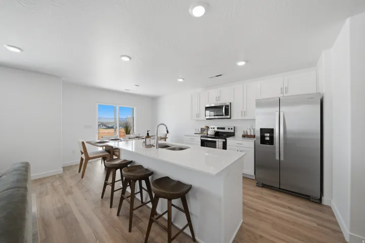 Kitchen featuring wood-finish flooring, white cabinetry, stainless steel appliances, and a central island with a solid surface countertop