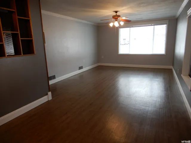 Spacious interior showcasing wood-finish flooring, light gray wall paint, and white crown molding