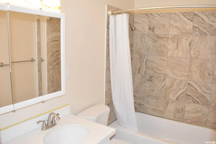 Bathroom featuring a shower/tub combination with patterned wall tiles