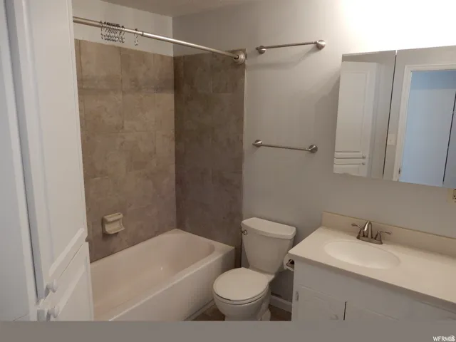 Full bathroom featuring a white vanity with integrated sink, brushed nickel faucet, and a large mirrored medicine cabinet