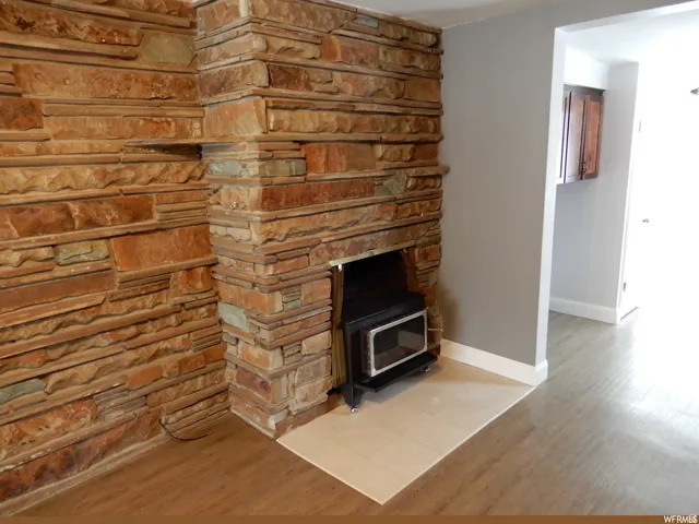 Stone-clad fireplace featuring a wood-burning insert and a hearth with light-toned tile