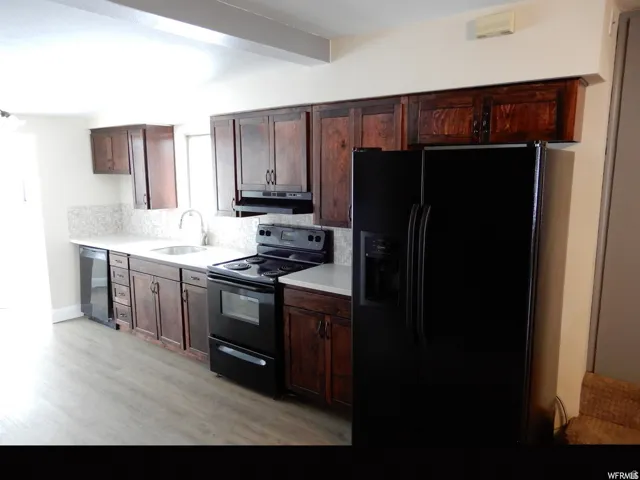 Kitchen featuring dark wood cabinetry, light countertops, a mosaic tile backsplash, and wood-finish flooring