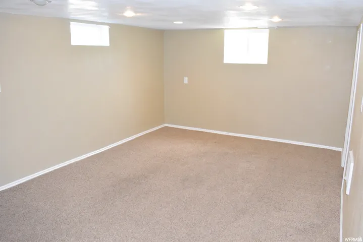Spacious room featuring neutral carpeting, light-colored walls, recessed lighting, and two transom windows