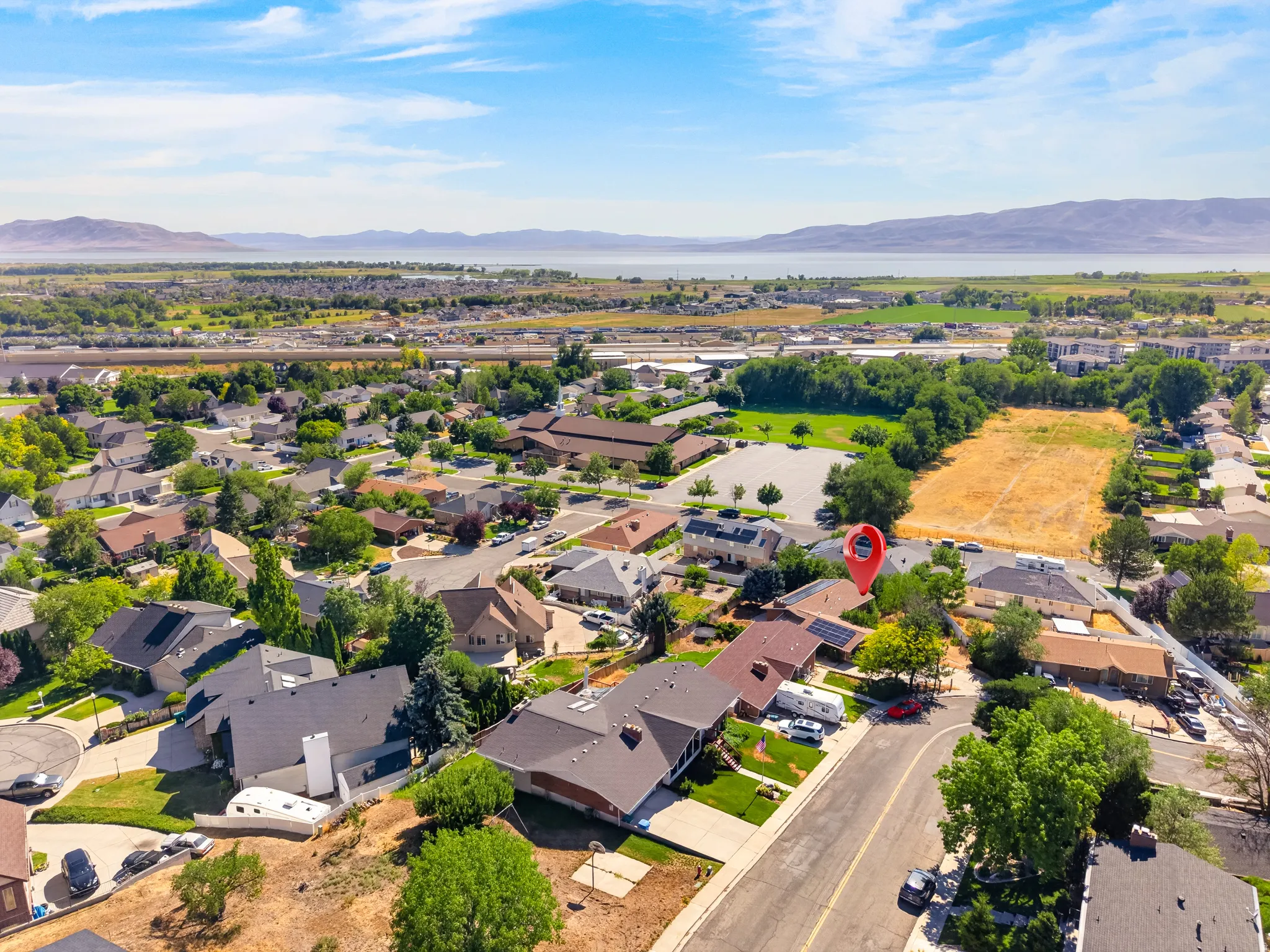 Aerial perspective of a residential neighborhood with distant mountains and a body of water