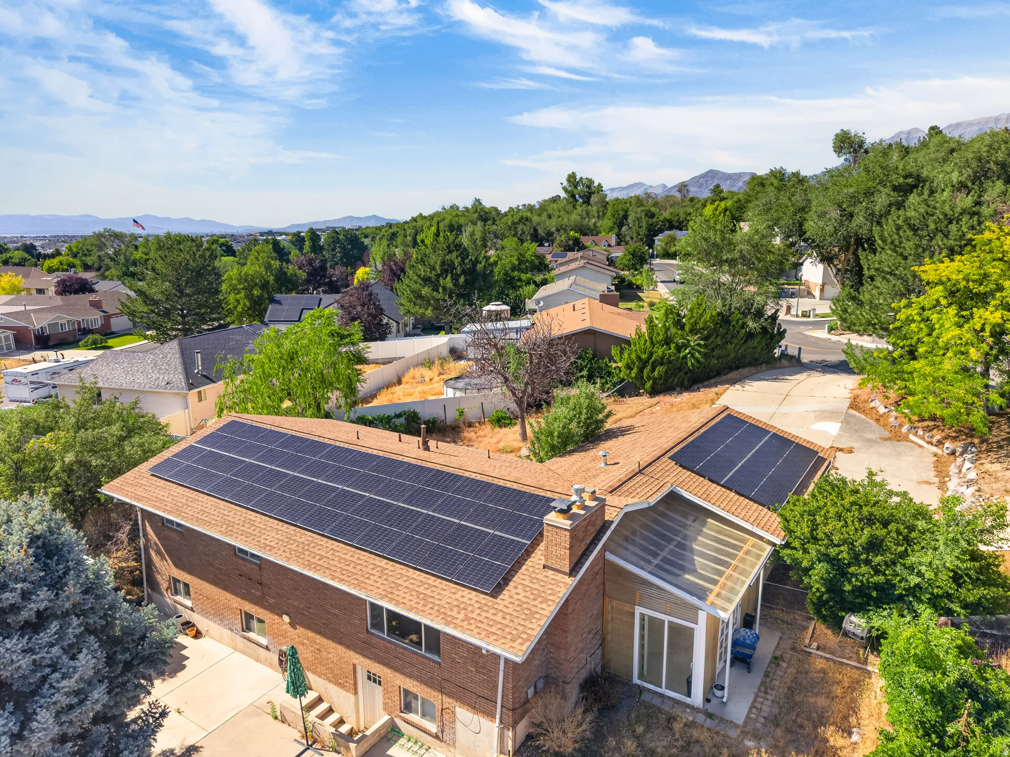 Property featuring a brick exterior and a brown shingle roof, equipped with multiple solar panel arrays
