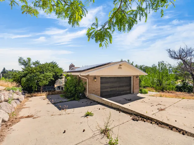 Attached two-car garage with a wood-finish door, brick exterior, and solar panels