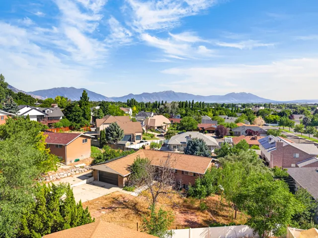 Residential neighborhood with diverse home styles, mature landscaping, and mountain backdrops
