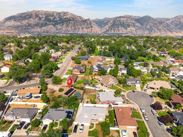 Residential neighborhood with varied architectural styles and abundant mature trees, situated against a dramatic mountain range backdrop
