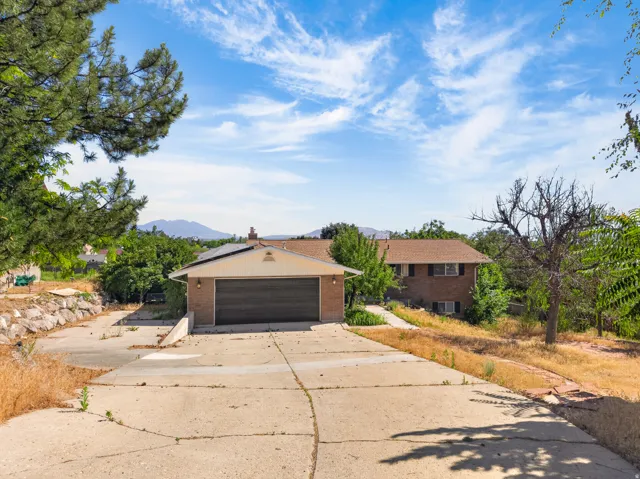 Brick exterior home with a two-car garage, concrete driveway, and mature landscaping