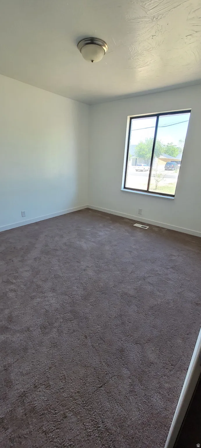 Room featuring wall-to-wall carpeting, white painted walls, and a large window with a black frame