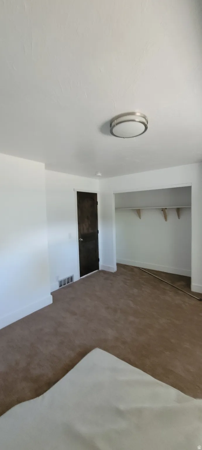 Spacious room featuring brown carpet flooring, white walls, and a contemporary ceiling light fixture