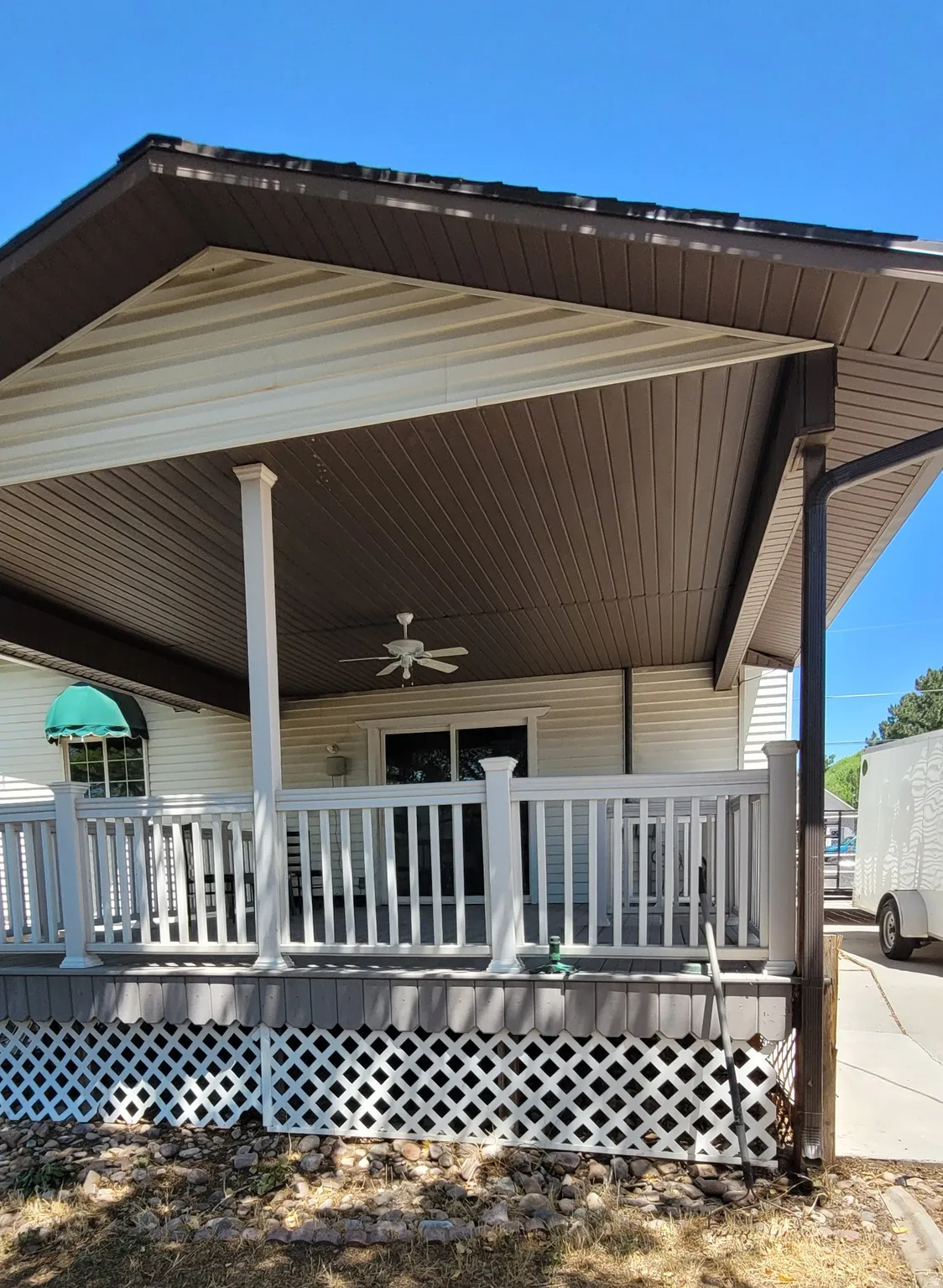 Covered porch featuring white railing, integrated ceiling fan, and sliding glass door access