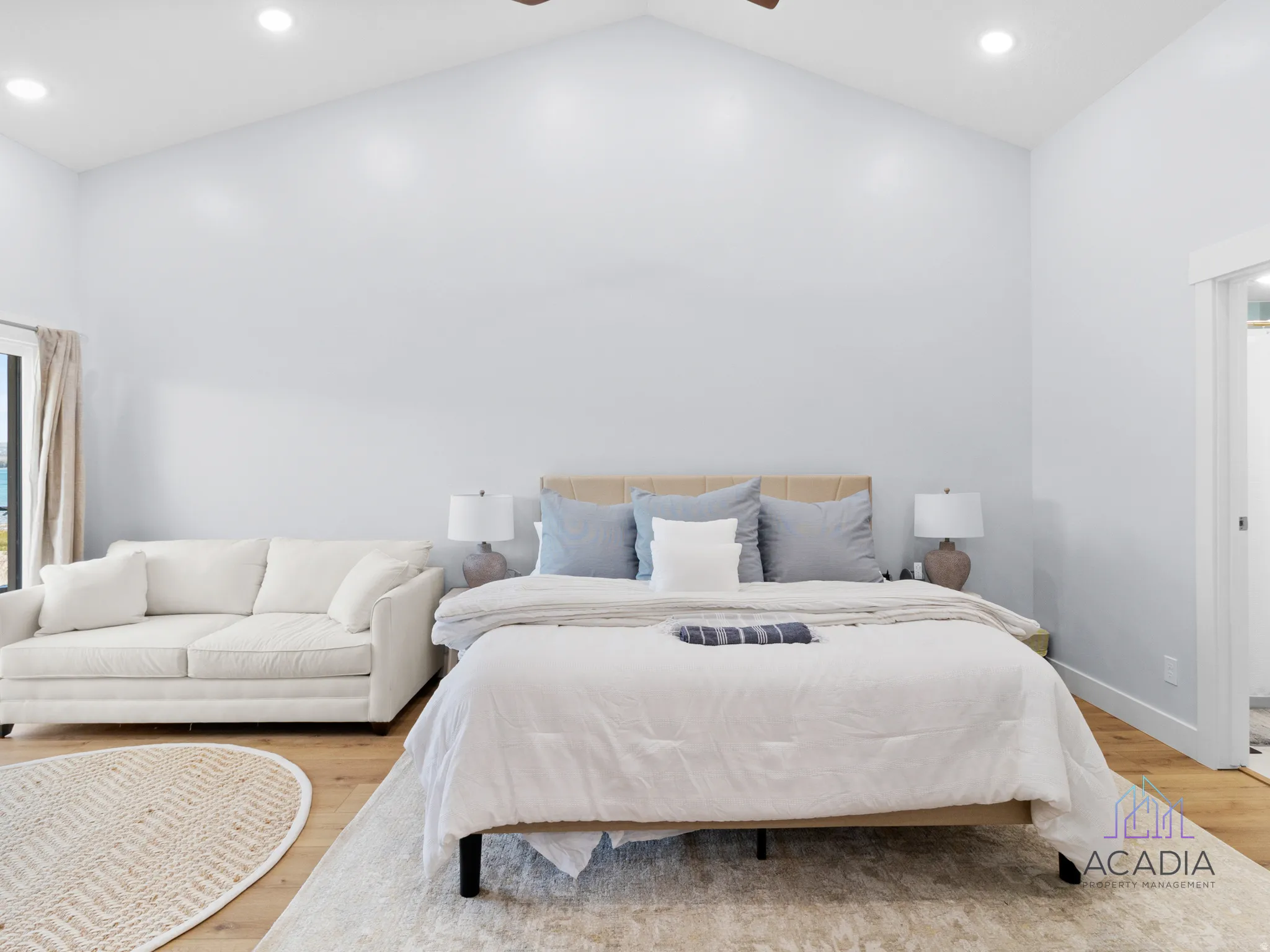 Spacious room featuring vaulted ceilings, recessed lighting, wood-finish flooring, and a large window with exterior scenery