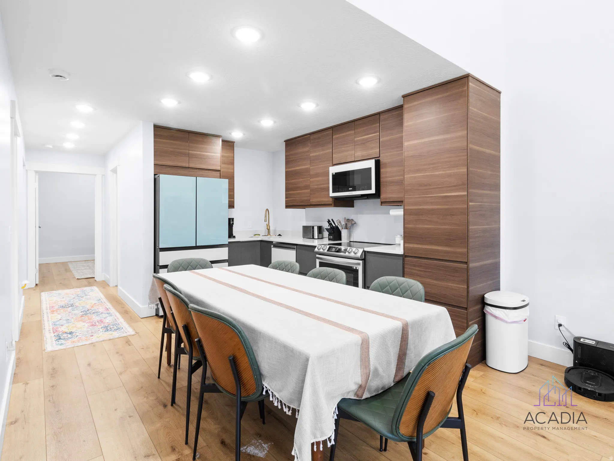 Open-concept kitchen and dining area featuring wood-finish flooring, recessed lighting, and a contemporary kitchen with wood-tone upper cabinetry and a light blue refrigerator