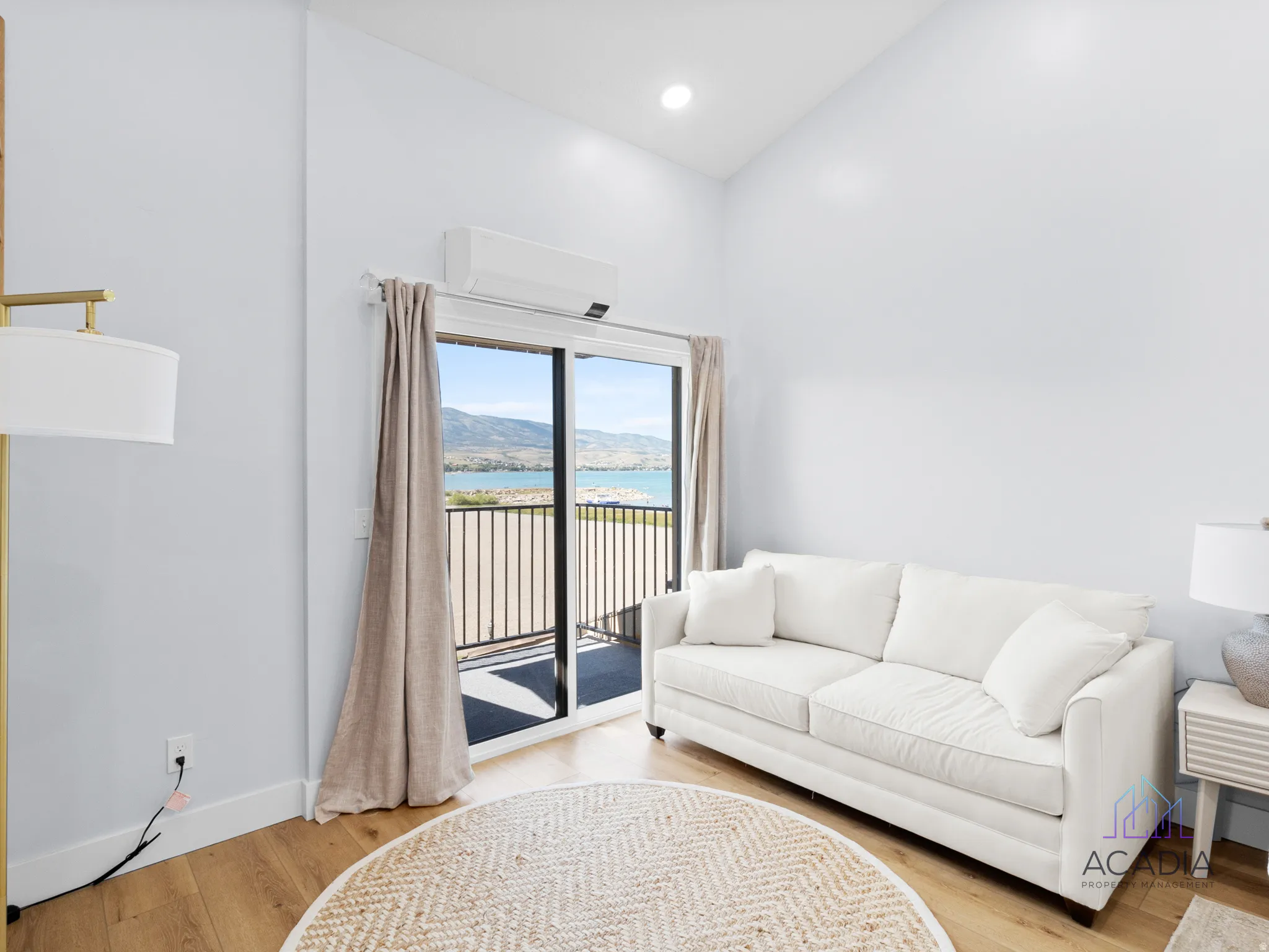 Spacious room featuring light wood-finish flooring, high ceilings, recessed lighting, and a sliding glass door opening to a private balcony