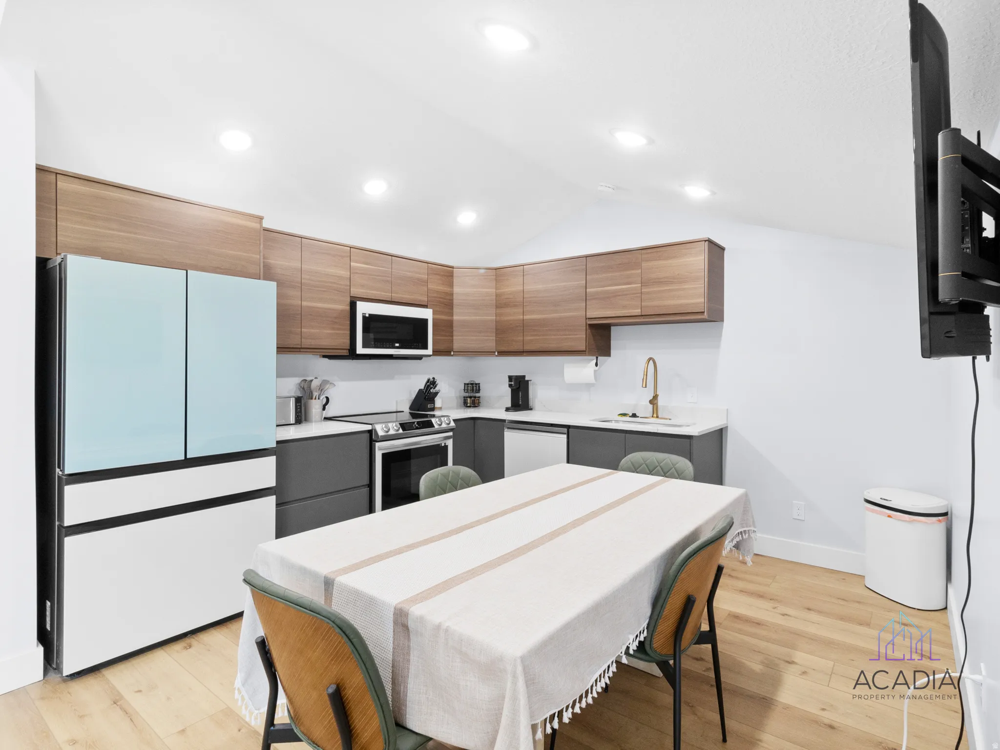 Modern kitchen featuring wood-finish upper cabinetry, matte gray lower cabinetry, and light-toned countertops