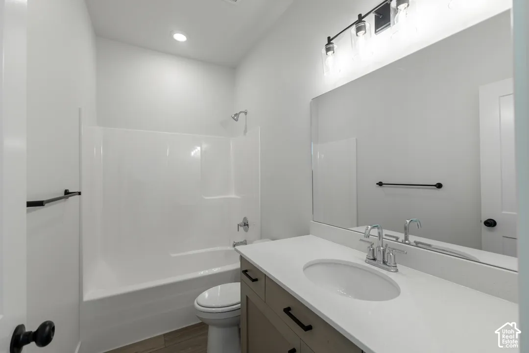 Bathroom featuring a light wood-finish vanity with a white countertop and undermount sink, a large wall-mounted mirror, and a white tub/shower combination