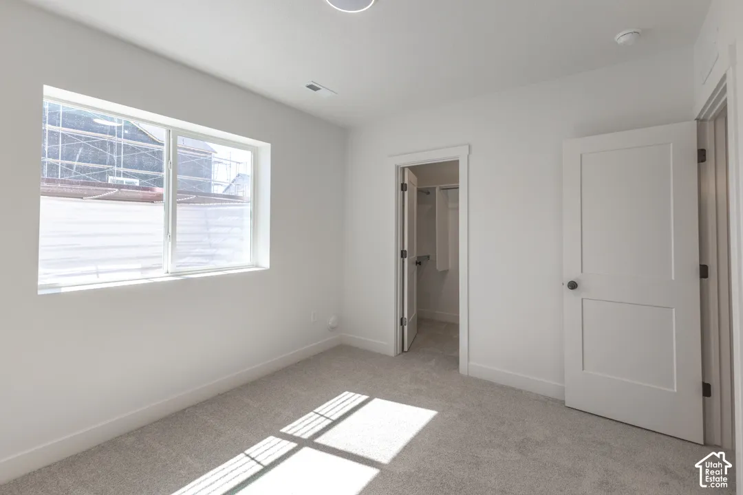 Carpeted room with a large window, a ceiling light fixture, a door with a black knob, and a separate closet with a bifold door