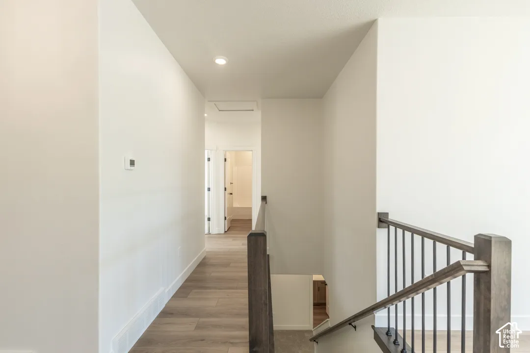 Hallway featuring wood-finish flooring, recessed lighting, and a modern thermostat