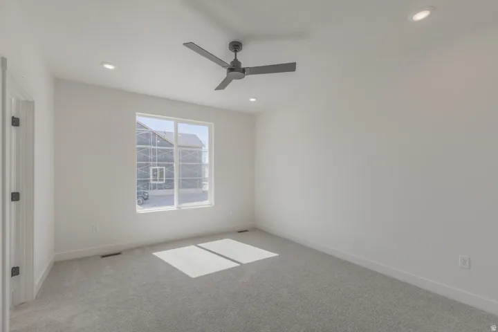 Bright room with a large window, light gray carpet, and a modern ceiling fan