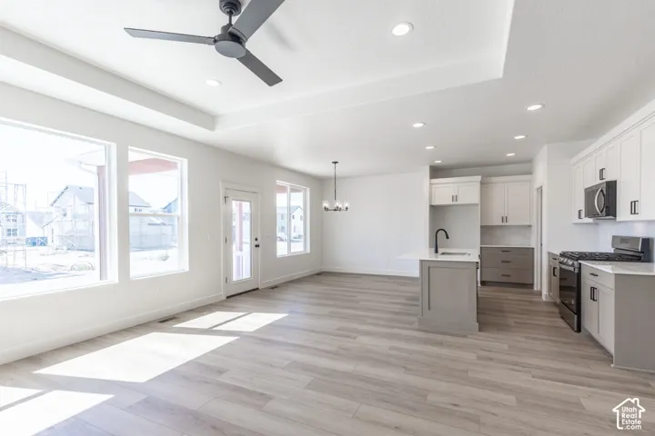 Open-concept living space featuring wood-finish flooring, recessed lighting, and a tray ceiling with a ceiling fan