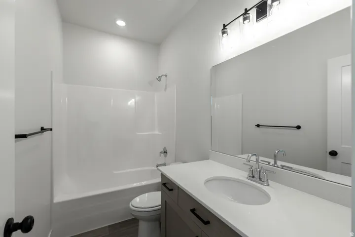 Bathroom featuring a single vanity with stone-look countertop, integrated sink, and wood-finish cabinetry