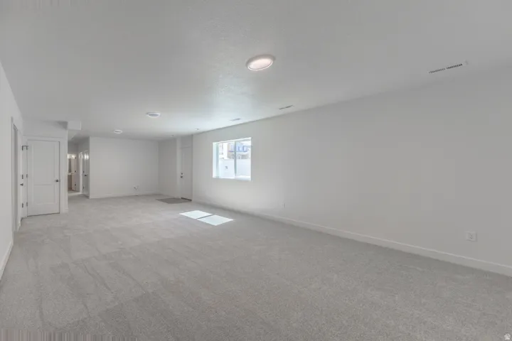 Spacious room featuring neutral carpeting and white walls