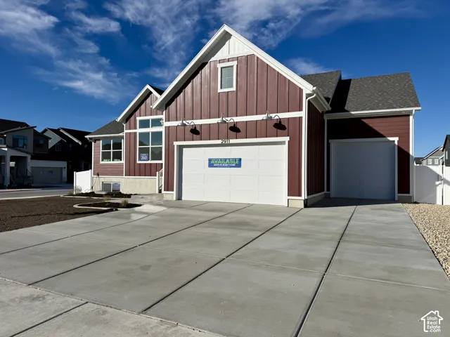 Board and batten siding, multiple-bay garage, concrete driveway, and exterior gooseneck lighting