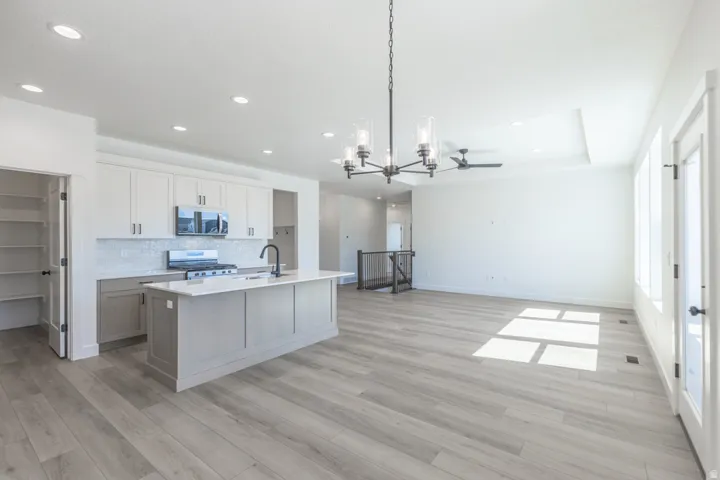 Open-concept living space with light wood-finish flooring, recessed lighting, and a tray ceiling