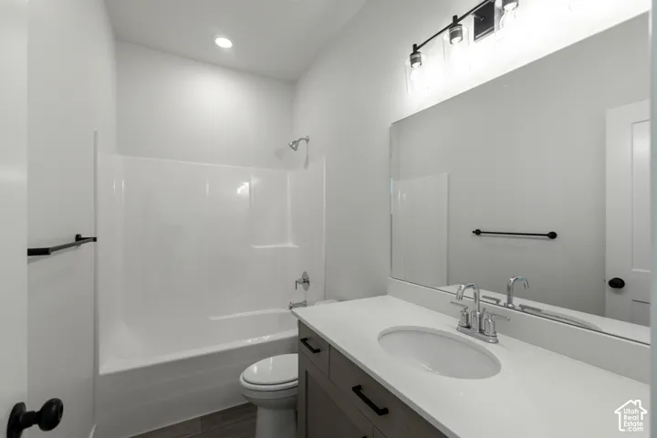 Bathroom featuring a single vanity with stone-look countertop, integrated sink, and wood-finish cabinetry