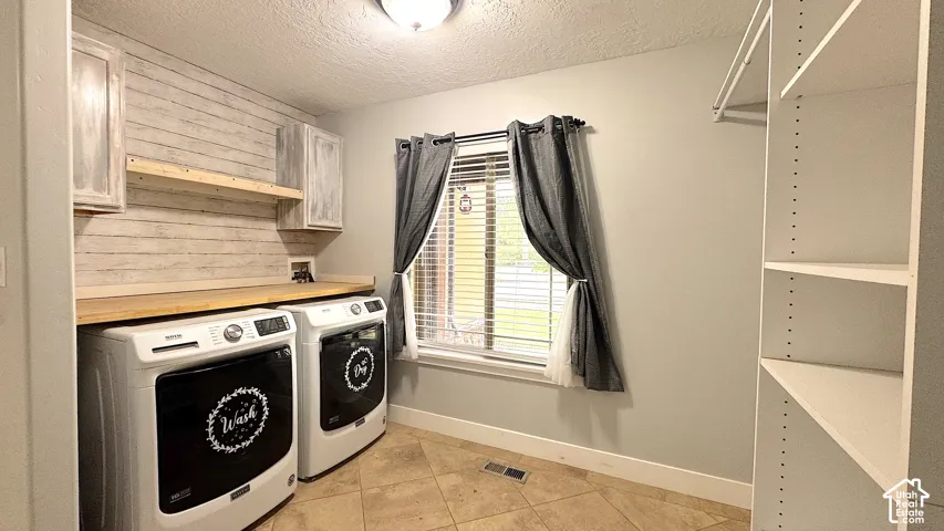 Laundry room, included washer & dryer, featuring tile flooring, a window with blinds, built-in shelving, a wood-finish countertop, and wall-mounted cabinetry.