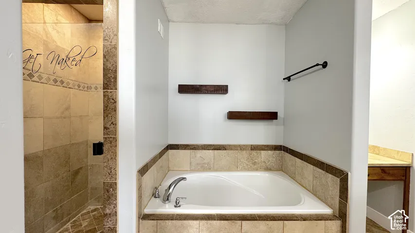 Tiled shower enclosure featuring a multi-function shower head, glass shower door, and separate decorative tile bath.