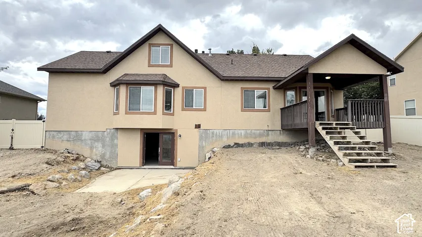 Rear of home, exterior featuring a covered deck with stairs, a bay window, and a ground-level entrance (Walk-Out) Basement with double doors.