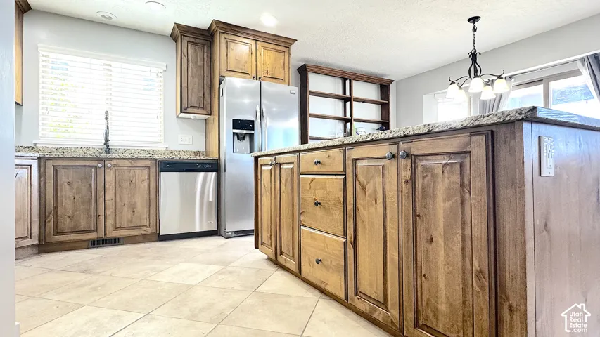 Kitchen featuring a central island with real natural wood cabinetry, light-toned tile flooring, stainless steel appliances, granite countertops, and a window with blinds