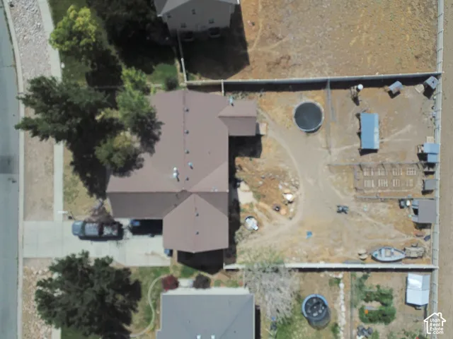 Property featuring a multi-gabled roof, paved driveway, mature landscaping, and a fenced perimeter