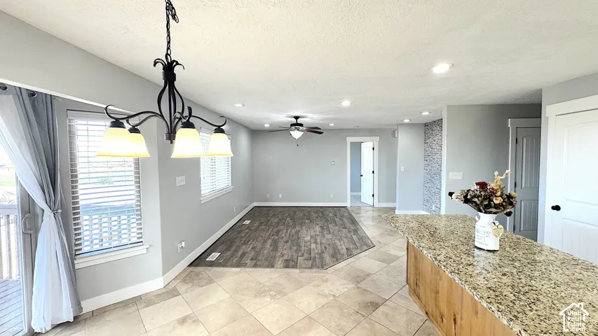 Spacious interior featuring a large kitchen island with granite-finish countertop, wood-finish base cabinetry, recessed lighting, and tile flooring