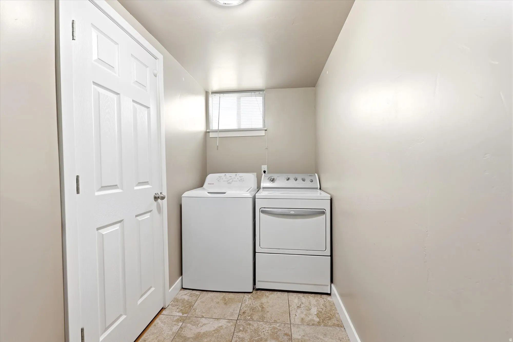 Dedicated utility area featuring tile flooring and a functional window