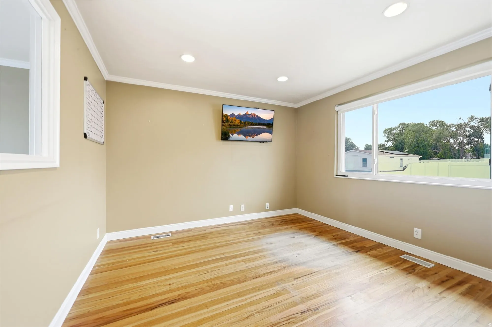 Spacious room featuring wood-finish flooring, recessed lighting, and a large picture window with white trim