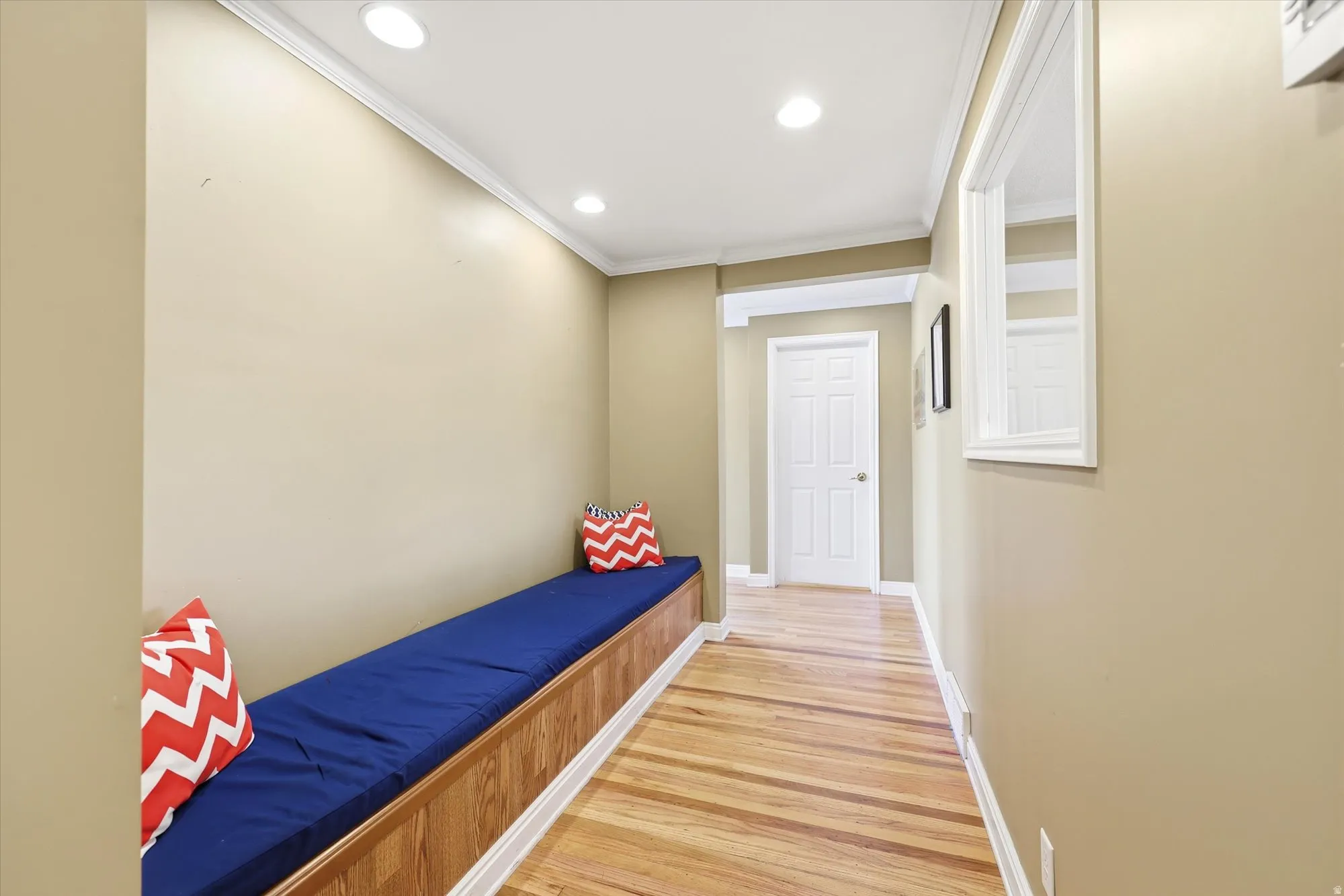 Hallway featuring an extended built-in bench, wood-finish flooring, recessed lighting, crown molding, and a paneled interior door