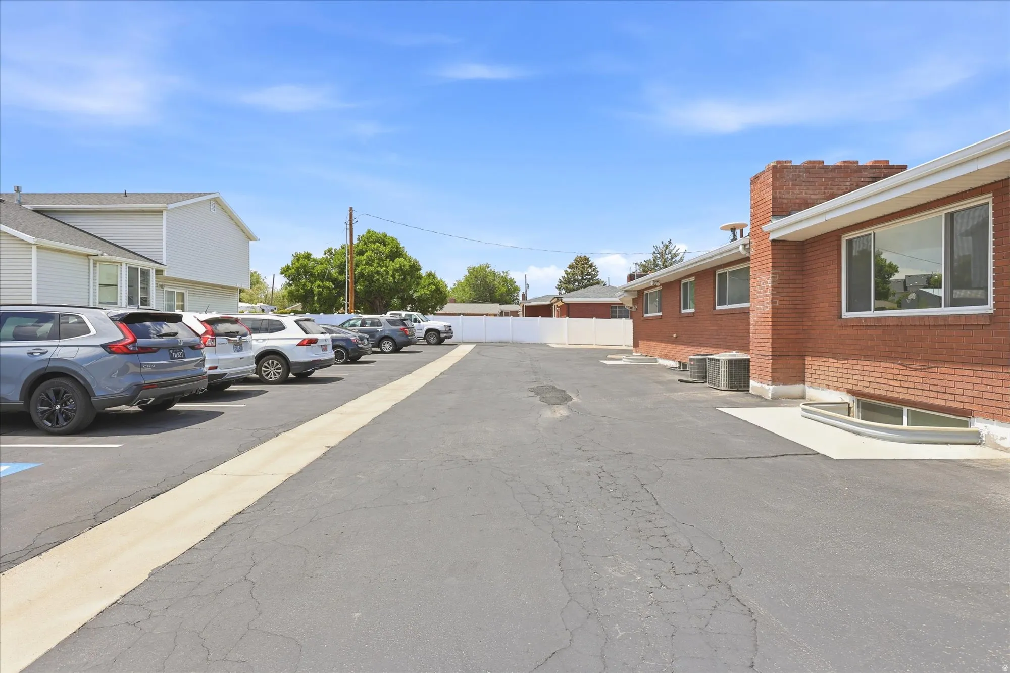 Expansive paved parking lot featuring marked spaces and a white perimeter fence